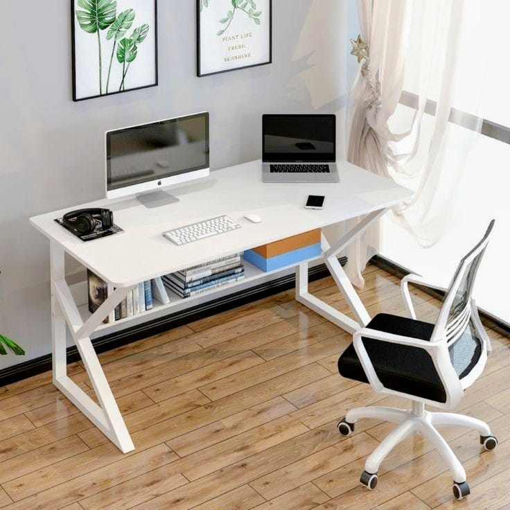 White office desk with computer setup in a room with light wood flooring and white walls.